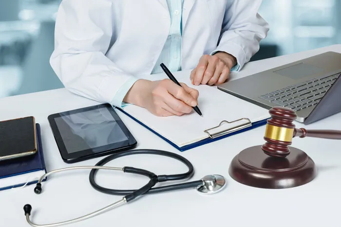 Doctor fills out a legal document in the office at the table.